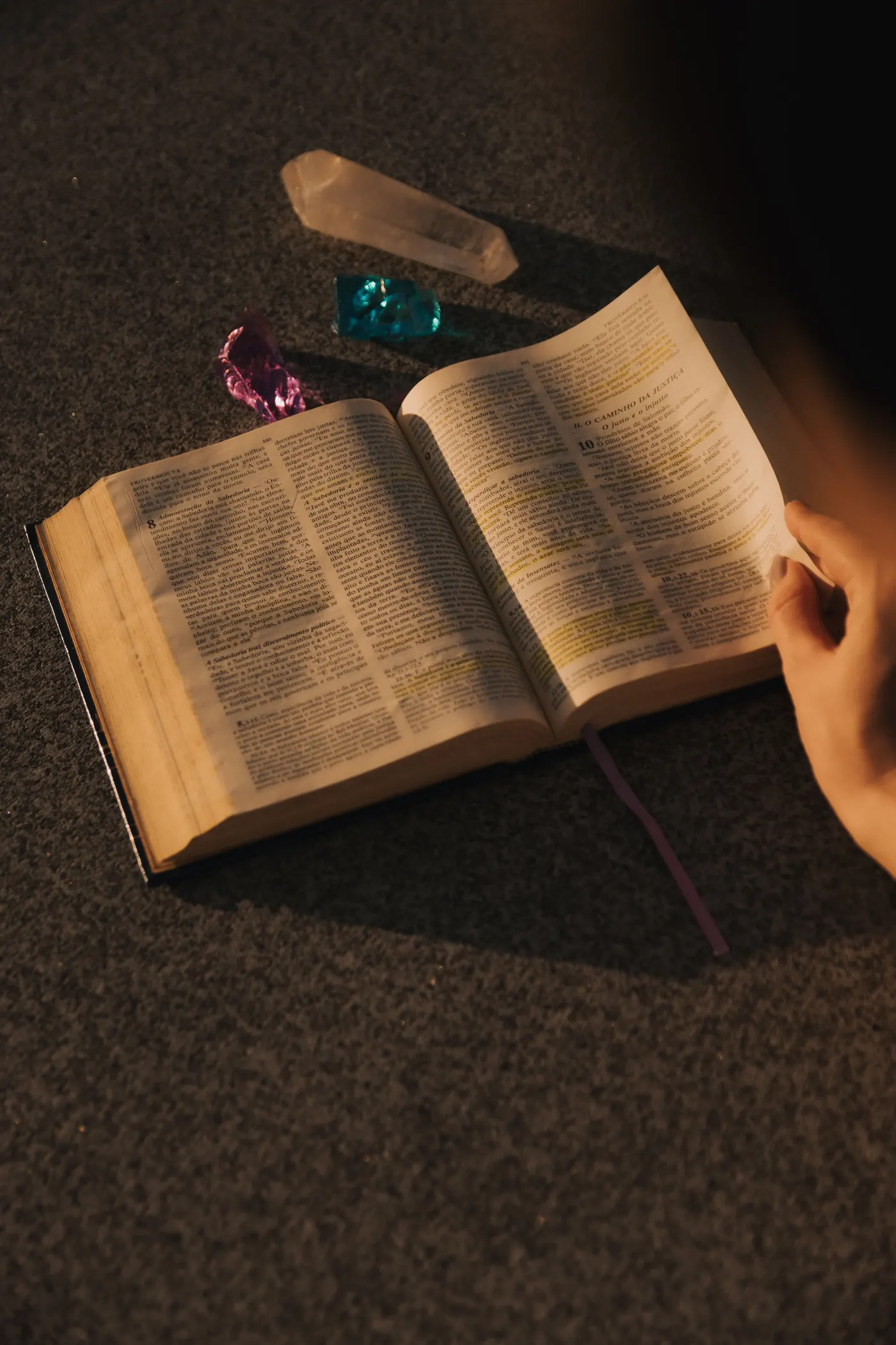 Livro aberto ao lado de cristais, à luz do fim de tarde